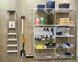 Estanterías y herramientas para saber como ordenar un garaje: escalera, pala, escoba, martillo, caja de herramientas, cubos y más.