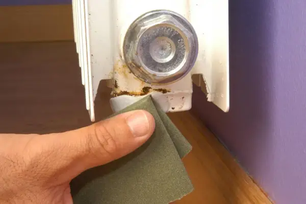 Lijando la zona oxidada de un radiador para prevenir una fuga.