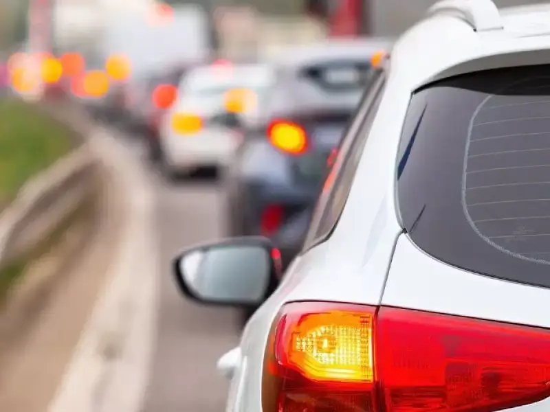 Un coche blanco en un atasco, con sus luces de freno rojas encendidas. ¿Cuántas luces de freno tiene un coche?